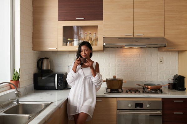 cocinas integrales; una mujer tomando un café dentro de la cocina